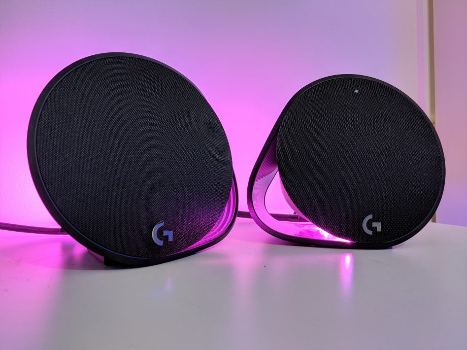 Logitech G560 Lightsync speakers with glowing pink lights.