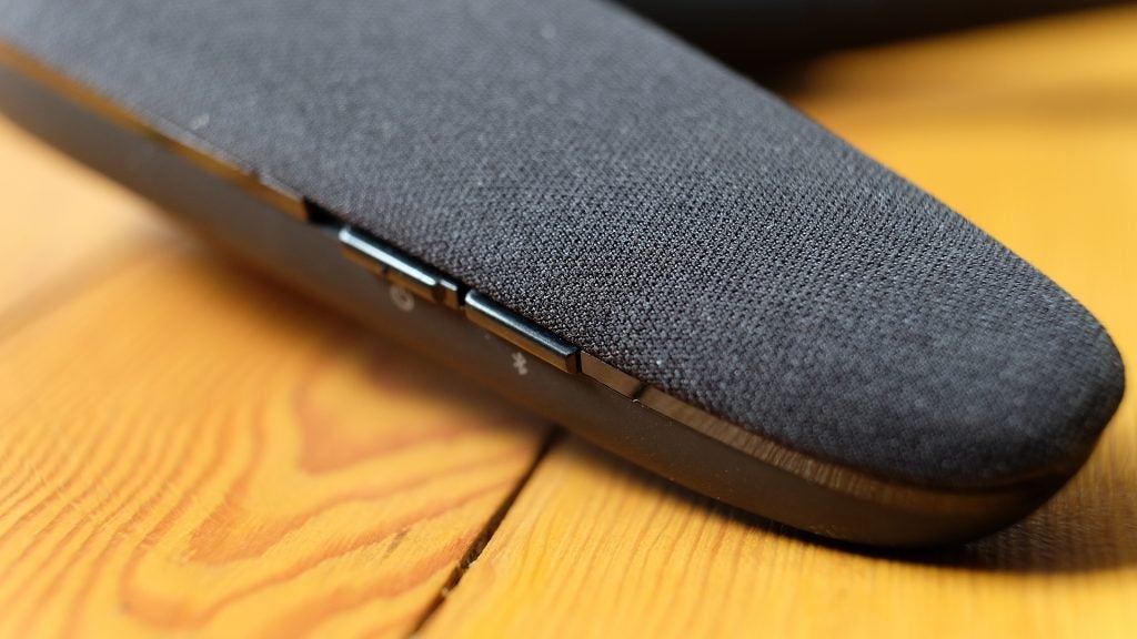 Close-up of JBL Soundgear wearable speaker on wooden surface.