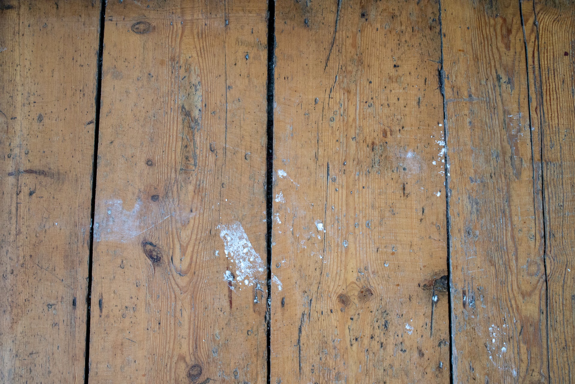 Dirty wooden floor planks with debris.