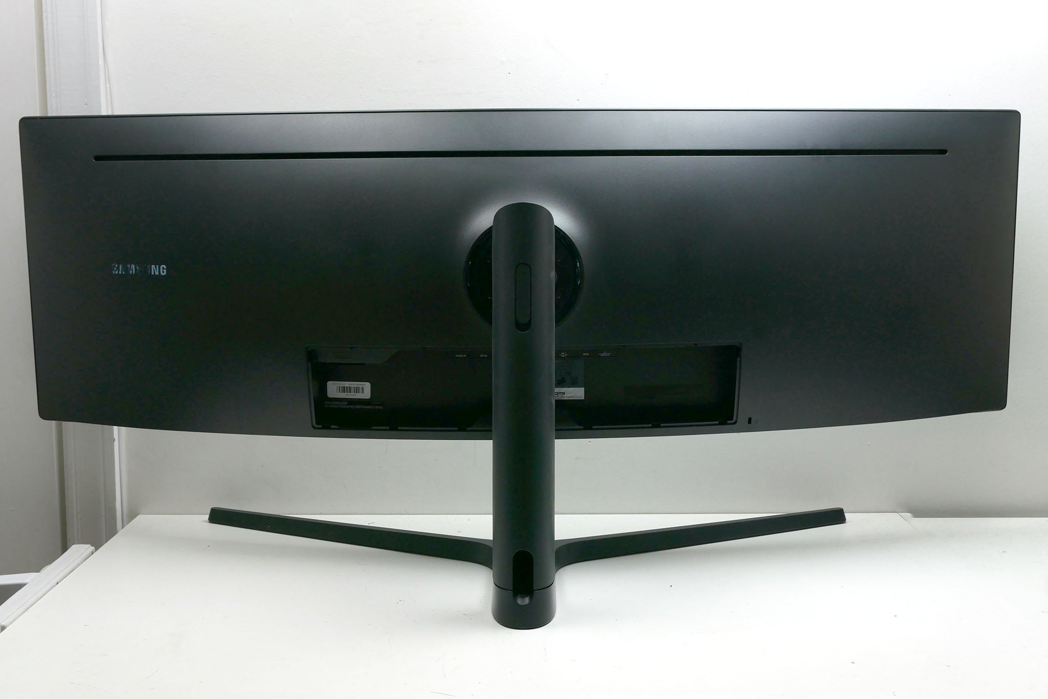 Samsung C49J89 monitor rear view with stand and ports visible.