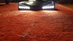 Shark vacuum cleaner LED headlights illuminating carpet dirt.