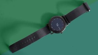 Skagen Falster smartwatch with black leather strap on green background.