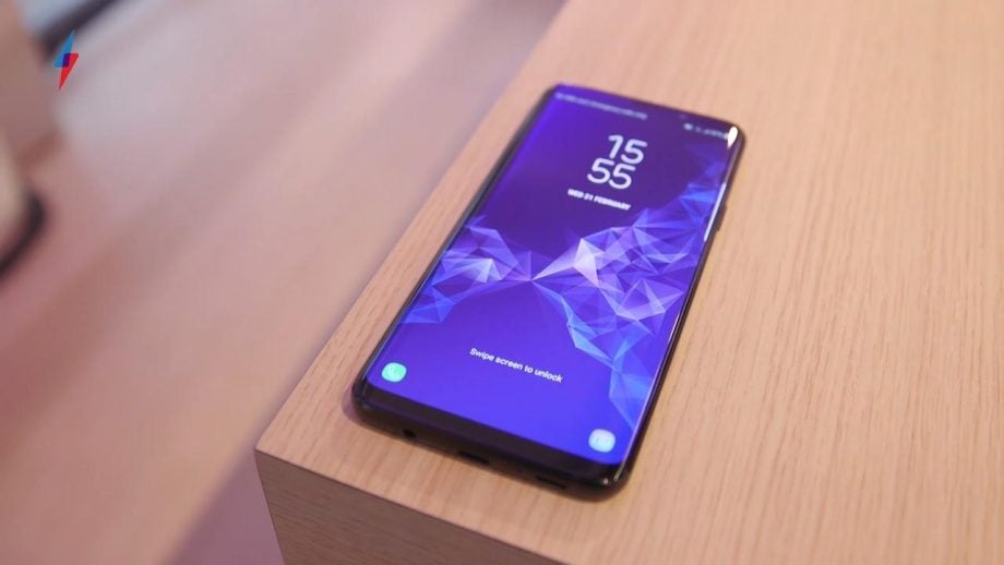 Samsung Galaxy S9 smartphone on wooden surface with screen visible.