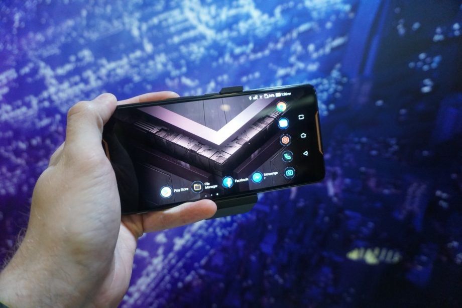 Hand holding an Asus ROG Phone displaying apps on screen.