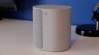 B&O Beoplay M3 speaker on desk with blue background.