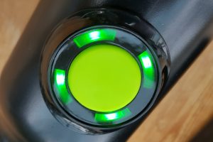 Close-up of Gtech Falcon lawnmower power button illuminated green.
