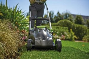Person mowing lawn with Gtech Falcon Cordless Lawnmower.Gtech Falcon Cordless Lawnmower on grass.