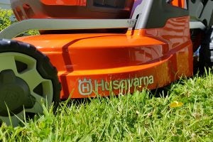 Close-up of Husqvarna LC 347VLi lawnmower cutting grass.