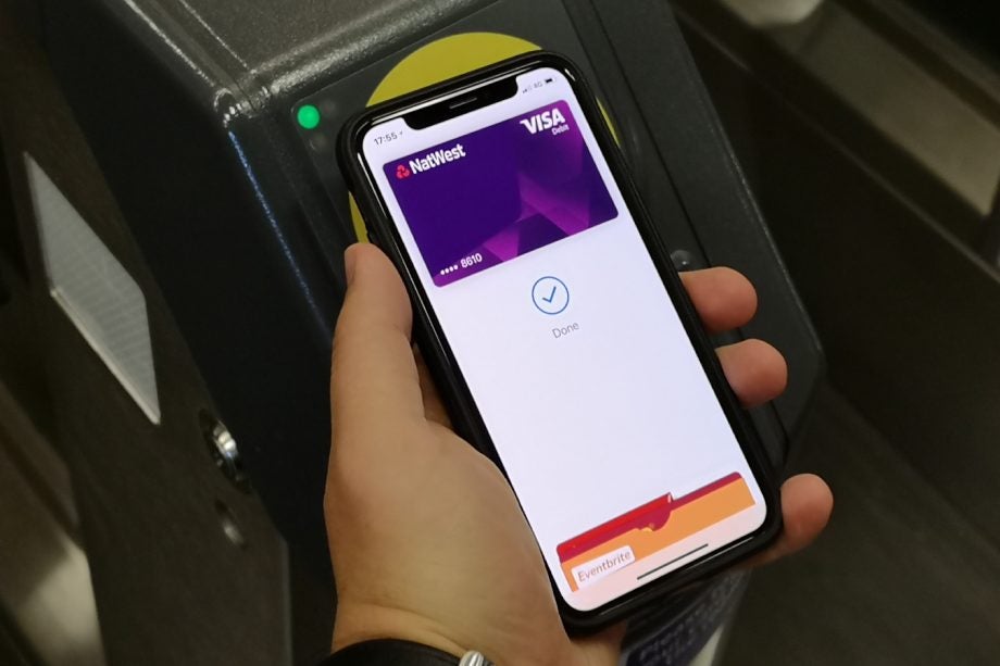 A black iPhone X held in hand displaying payment done via Appe pay, showing contactless payment