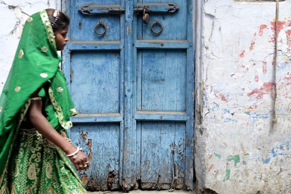 A young woman wearing a green traditional dress walking in front of a door