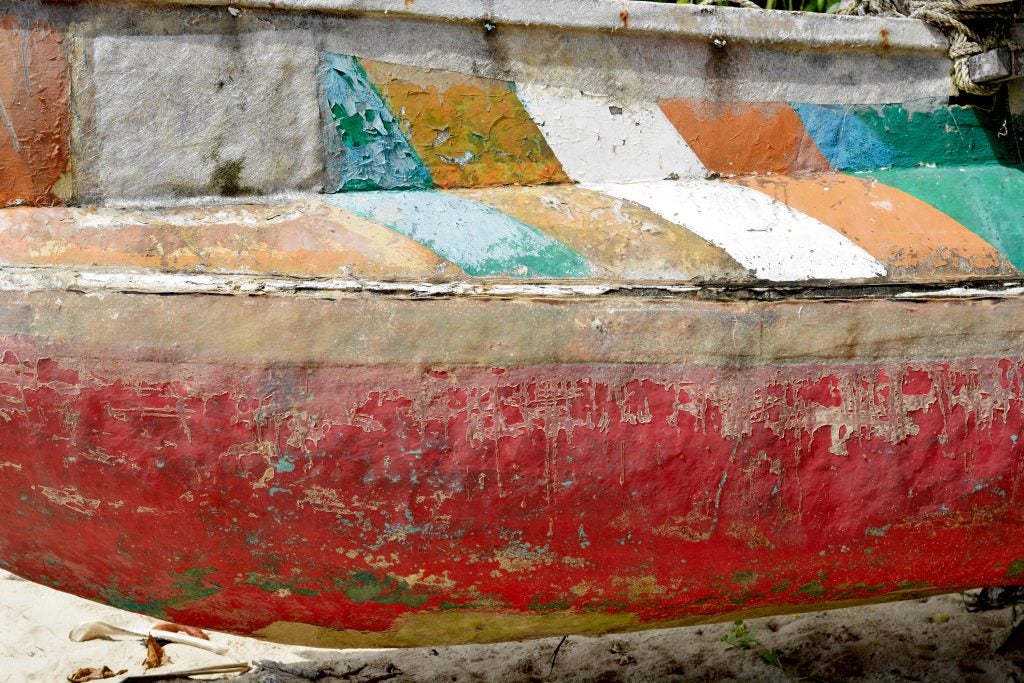 A wall with ancient human drawings on it and a golden window at the centerClose up side view of an old painted colorful boat
