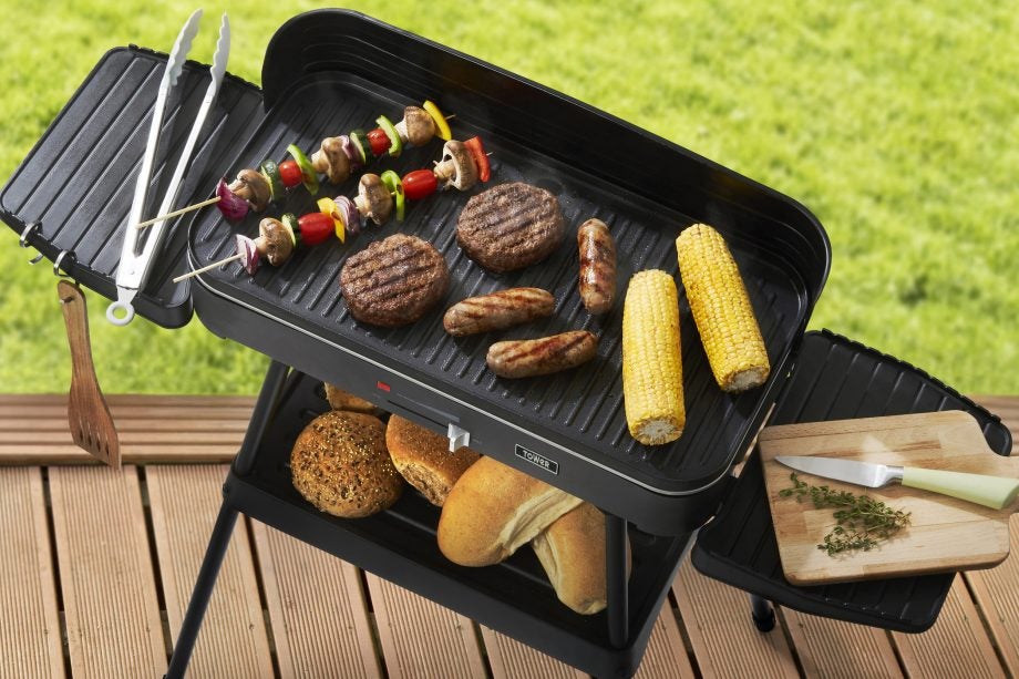 View from top of a black Tower T14028 with stand with stand standing on floor with different food items being grilled on it