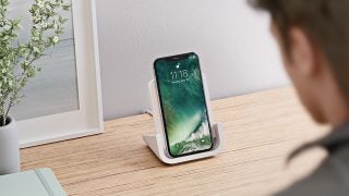 An iPhone kept on a wireless charging stand kept on a table displaying lock screen