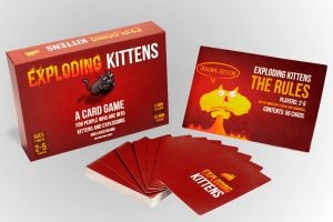Box and cards of a card game called Exploding Kittens kept on a silver background