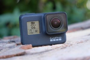 A blue GoPro Hero7 camera standing on a wooden surface