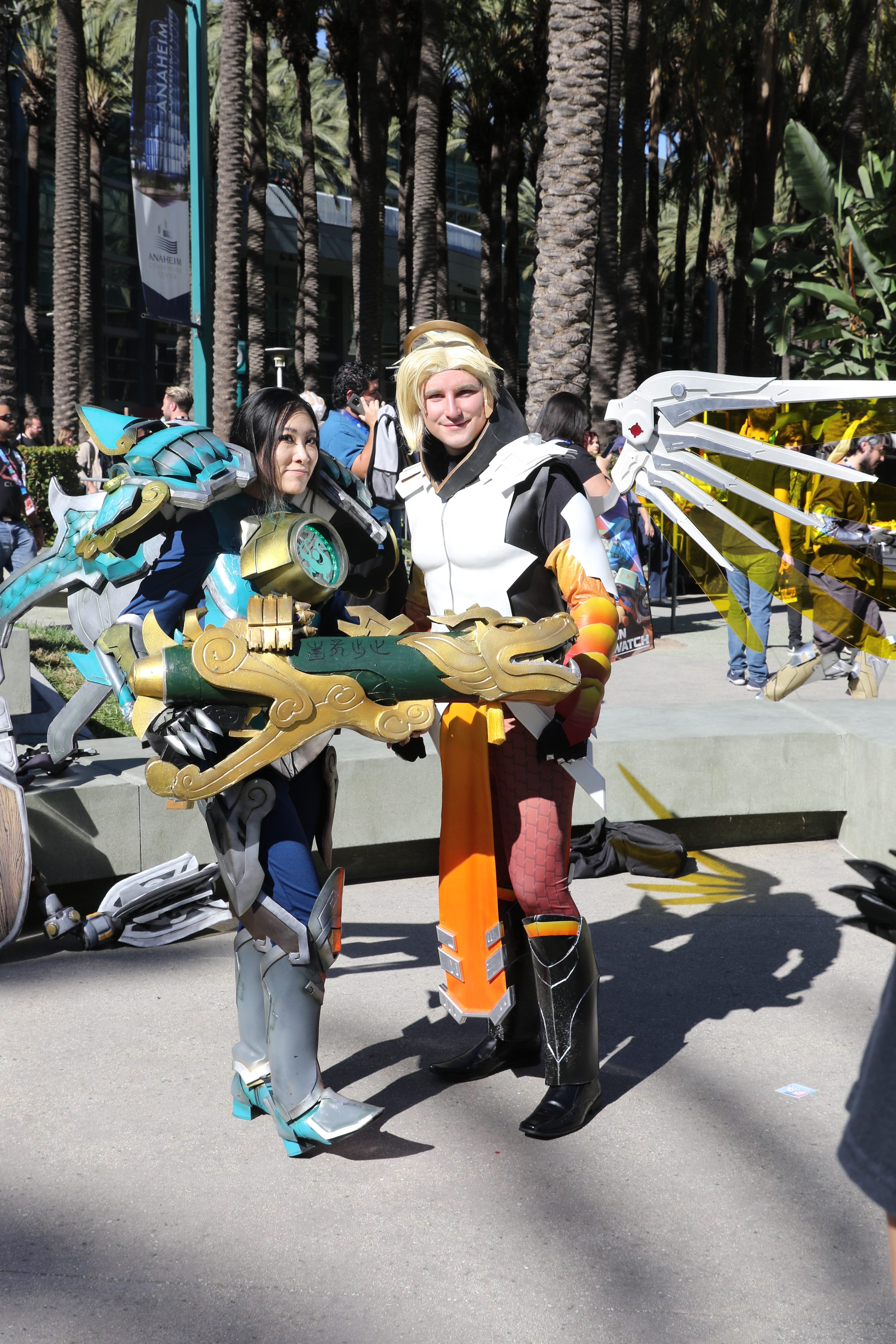 Two women dressed as Pharah and Mercy standing on a street