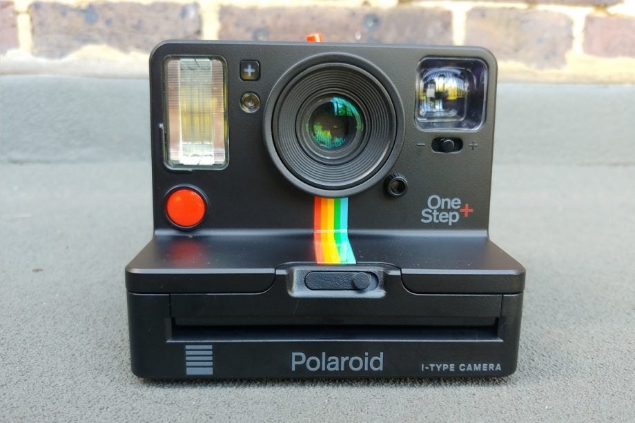 A black Polaroid One Step+ camera standing on floor
