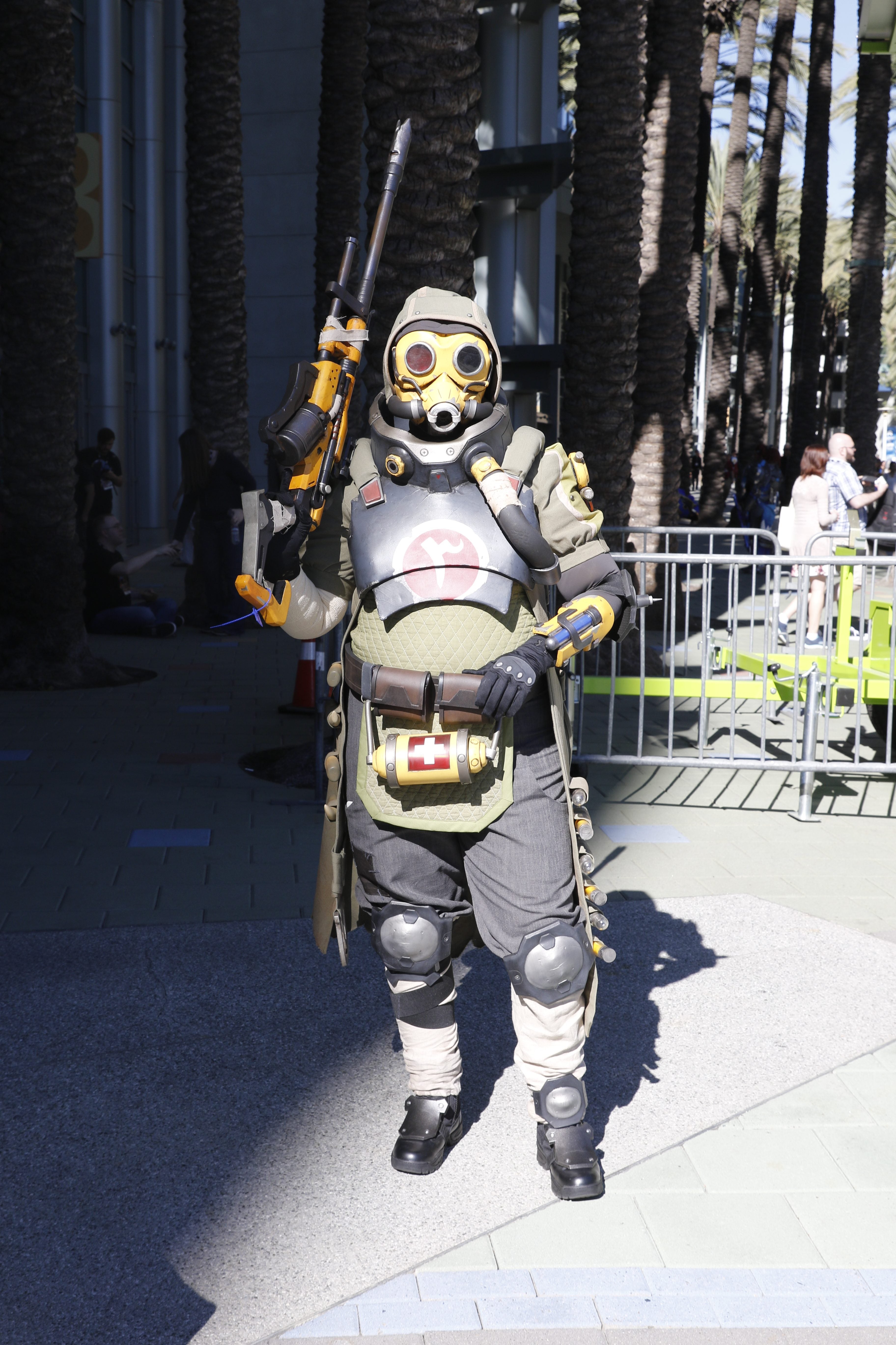 A person wearing an alien suit holding a rifle standing on a street