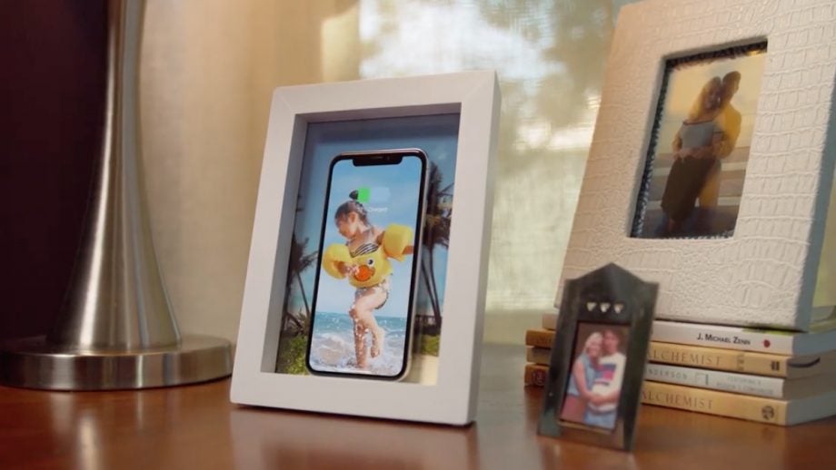 A white photo frame shaped TwelveSouth PowerPic wirless iPhone charger standing on a table