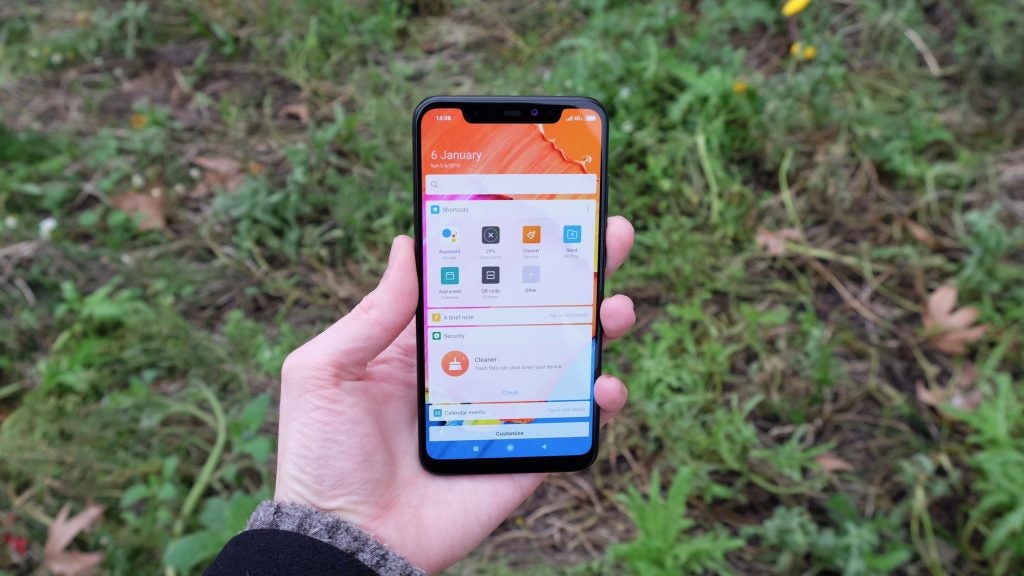 Hand holding Xiaomi Mi 8 smartphone displaying home screen outside.