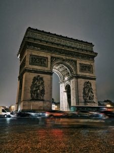 Arc de Triomphe at night with light trails from passing cars.