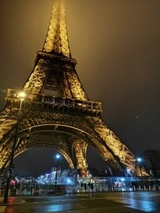Illuminated Eiffel Tower at night with pedestrians below.