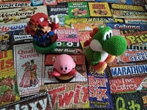 Plush Yoshi, Kirby, and Mario figures on a candy wrapper collage.
