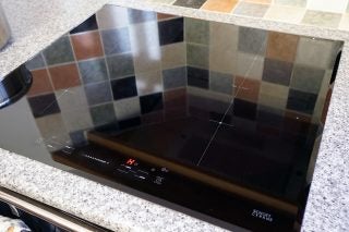 Sharp induction hob with touch controls installed on kitchen counter.