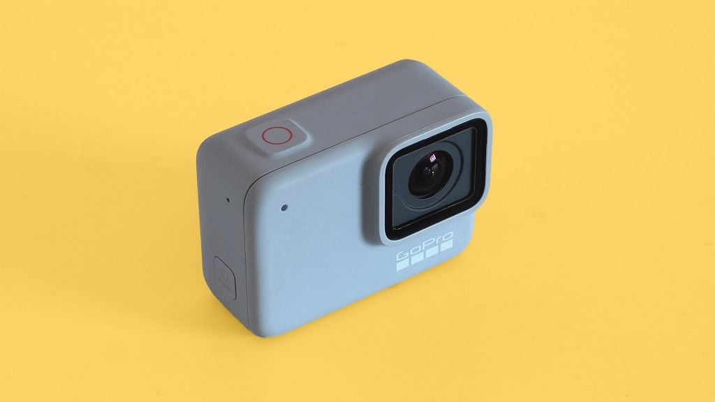 Left-top angled view of a GoPro Hero7 white standing on a yellow backgroundLeft and bottom edge view of a GoPro Hero7 white laid on a yellow background