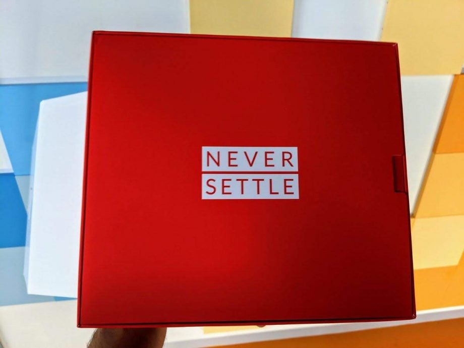 A red box with Never Settle written on it held in hand raise in air