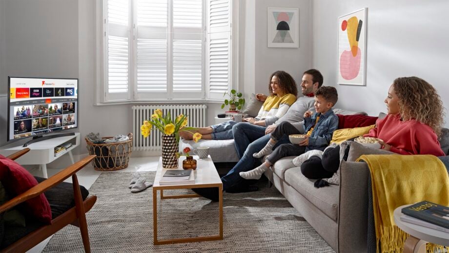 Picture of a room with a family sitting on a couch and a TV displaying content from FreeviewPlay