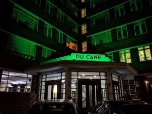 Picture of a building at night named DU CANE COURT with cars parked on the front