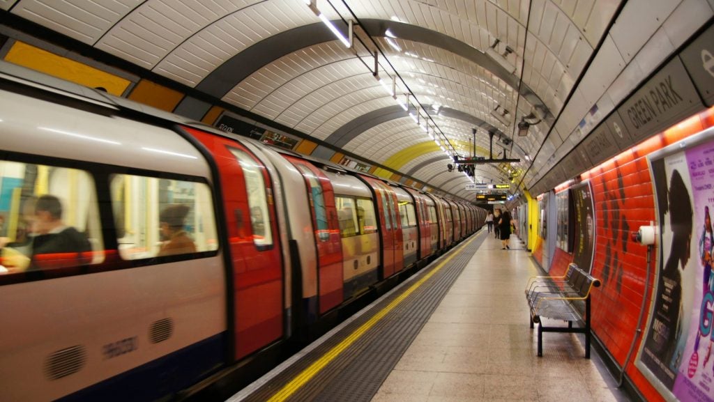 A London subway with a metro running on left an d people walking on platform on right