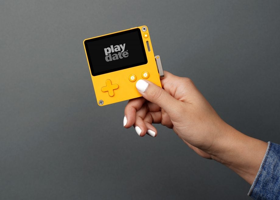 A yellow Playdate console held in hand