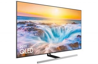 Left angled view of a black Samsung QE65Q85R TV standing on a white background