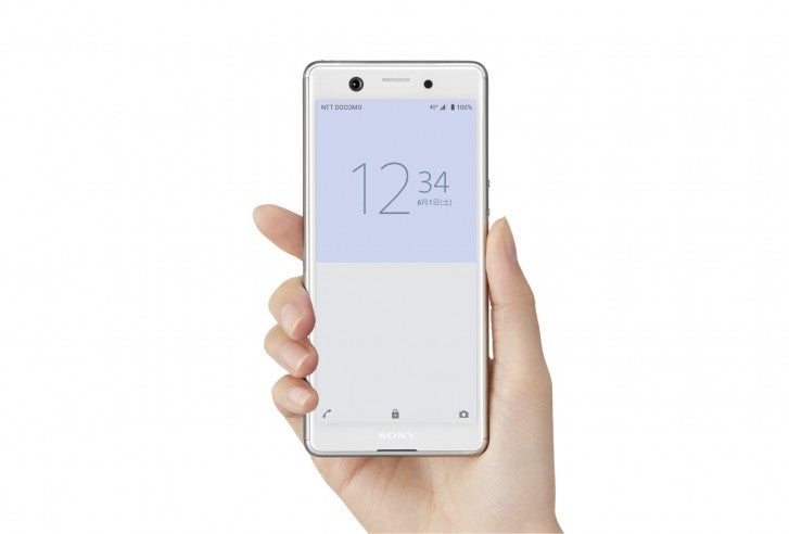 A white Sony Xperia Ace held in hand on a white background displaying lock screen