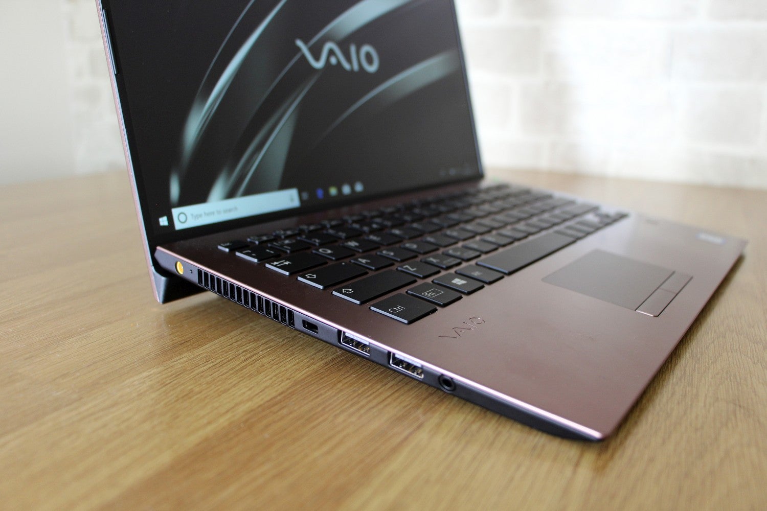 Left side edge view of a brown Vaio SX14 laptop kept on a table diplaying homescreen