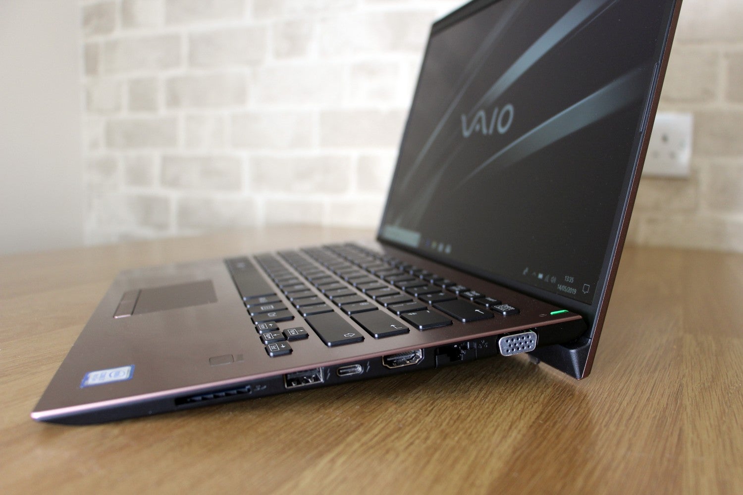 Right side edge view of a brown Vaio SX14 laptop kept on a table diplaying homescreen