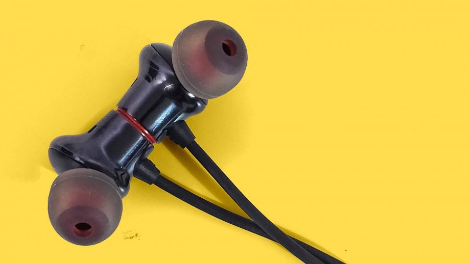 Close up view of OnePlus Bullets wireless 2 earphones's earbuds kept on a yellow background