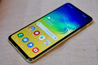 Right angled view of a Samsung Galaxy S10e laid on a surface displaying homescreen