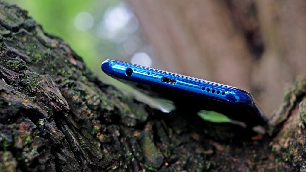 Bottom edge view of a blue Honor 20 Lite kept on a wooden surface
