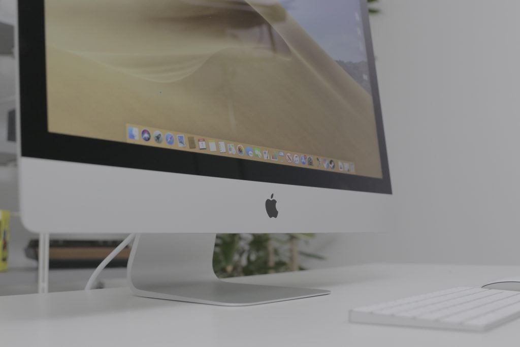 Close up view of an iMac's bottom bezel, standing on a white table