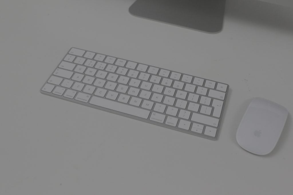Close up view of iMac's keyboard and mouse kept on a white table