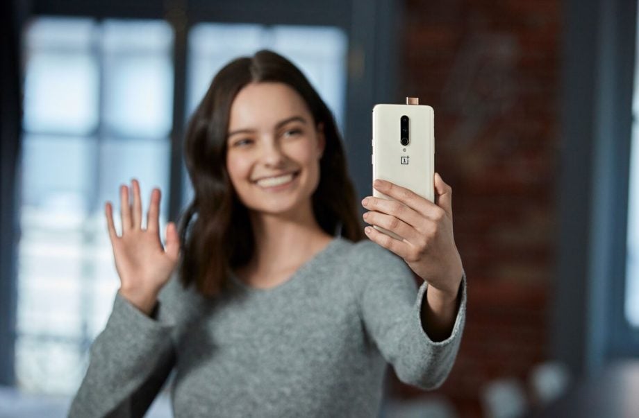 Back panel view of a white OnePlus 7 Pro held in hand with selfie camera popped-out