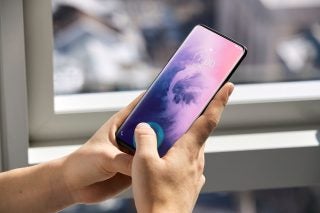 A black OnePlus 7 Pro held in hand displaying lock screen