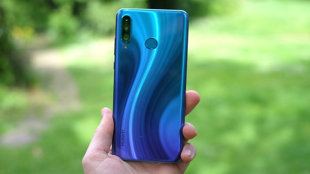 Back panel view of a blue Huawei P30 Lite held in hand facing back