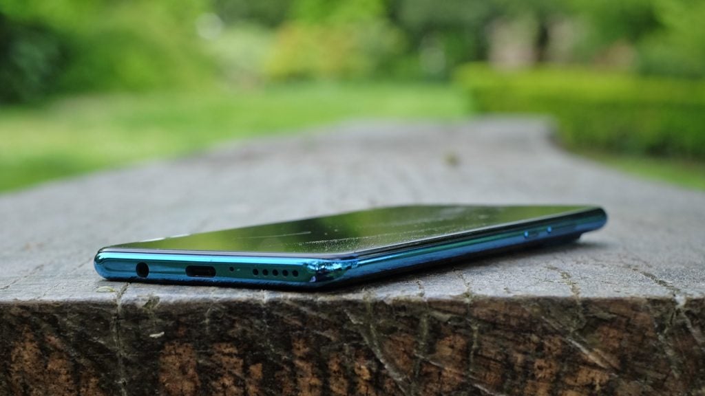 Bottom and side edge view of a blue Huawei P30 Lite kept on a wooden surface