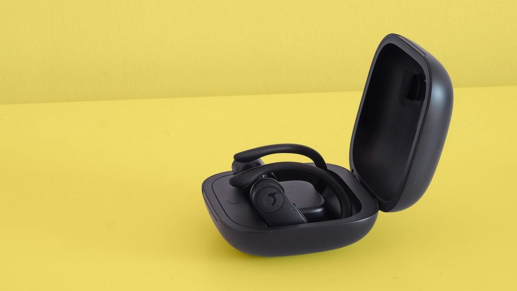 Powerbeats ProSide view of black Powerbeats earbuds kept in it's case on a yellow background
