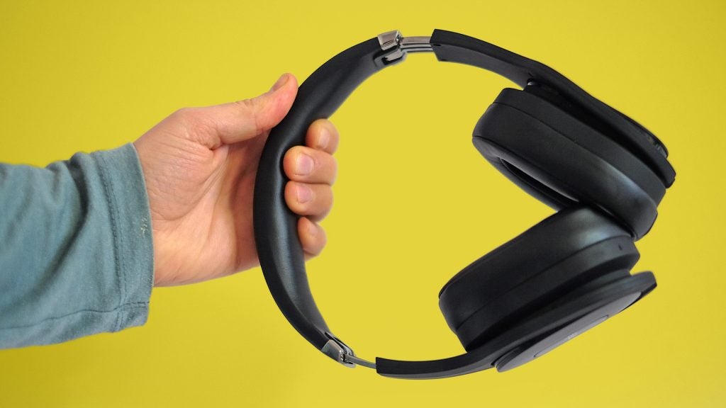 PSB M4U 8Black PSB headphones held in hand on a yellow background