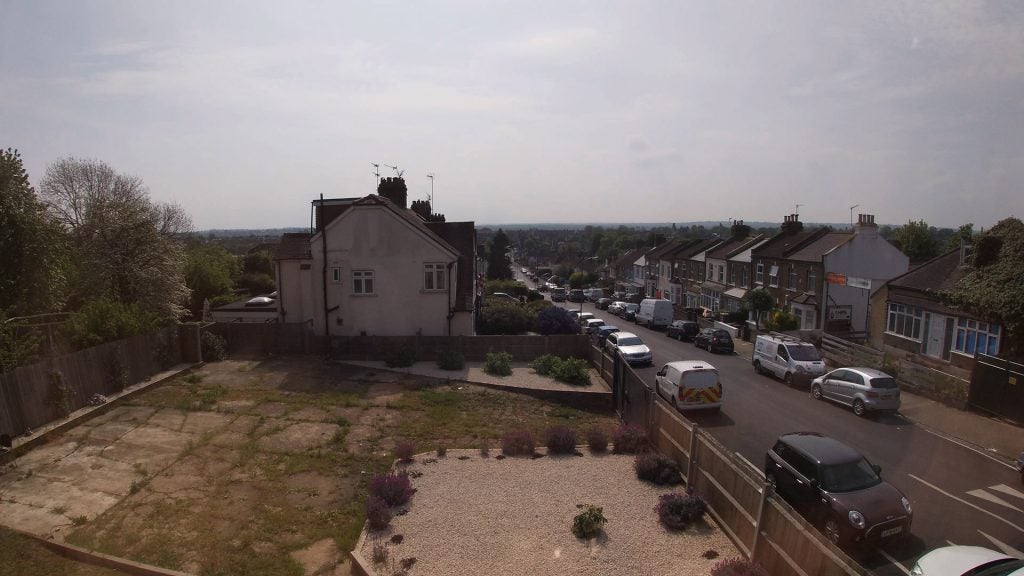 View from top of a colony with similar houses on either sides of a road with cars parked on the front